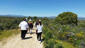 6 personas andando por senda de tierra que atraviesa monte bajo.