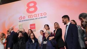 Isabel Diaz Ayuso con un grupo de personas delante de un cartel del 8 de marzo