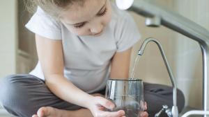 niña con un vaso cogiendo agua del grifo