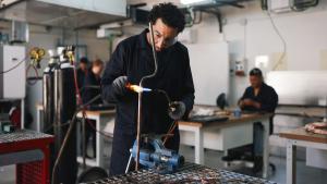 Hombre soldando un tubo de cobre con soplete en un taller