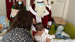 Personas caracterizadas de papa noel y su ayudante junto a una mujer y su bebé