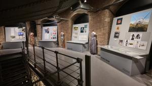 Vista de una sala de exposiciones con maniquíes, diseños de moda y escaleras de acceso