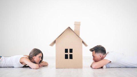 Dos personas mirando una caja en forma de casa
