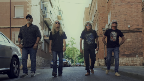 Fotograma del documental que muestra a los cuatro miembros de la agrupación musical paseando por un paisaje de barrio madrileño