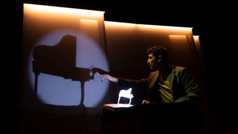Fotografía del mago tocando el piano en una sombra proyectada sobre una pantalla