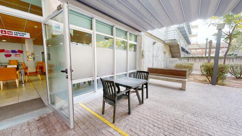 Acceso del centro de día. Acceso con puertas de cristal y espacio de esparcimiento en la terraza.