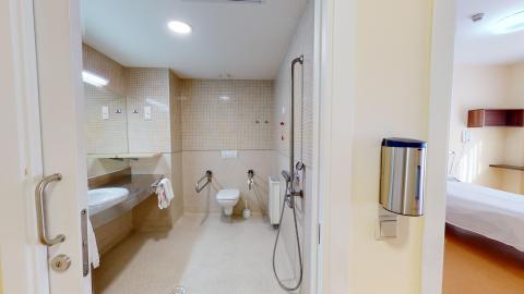 Baño y aseo. A la izquierda el lavabo, al fondo el inodoro y a la derecha la ducha con muro de azulejos.