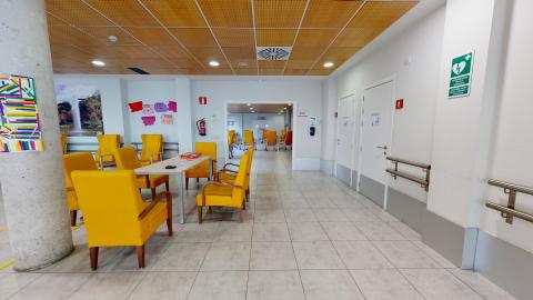 Sala de estar. Estancia amplia y luminosa con ventanas y sillones individuales con brazos y rueditas. Mesas cuadradas para convivencia.