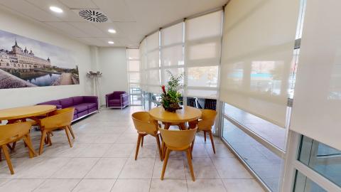 Mirador. Amplio pasillo techado con ventanales de suelo a techo. Hay mesas, sillas y sofás para descanso y esparcimiento.