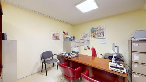 Espacio en amarillo claro con un escritorio de atención en ele y varios archiveros. 