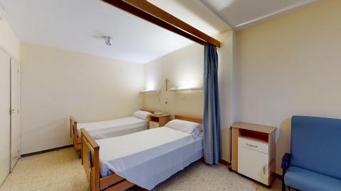 Habitación doble. Amplia habitación doble en colores claros. La zona de las dos camas individuales con mesilla de noche entre ambas se puede cerrar con cortinas para mayor intimidad. A la derecha otra mesilla y butacón individual.