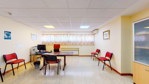 Unidad de psicología. Consulta de psicología en amarillo claro. Al fondo ventanas luminosas, al centro el escritorio de atención.