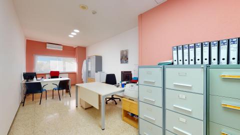 Unidad de trabajo social. Consulta de trabajo social con escritorio al fondo y otro a la derecha. En el muro del fondo hay una ventana amplia a exterior. En el muro de la entrada a la derecha, hay archiveros metálicos. Los muros son unos blancos y otros rosa anaranjado.