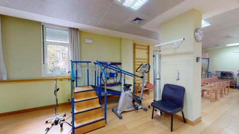 Fisioterapia. Espacio alargado en verde claro con un muro angosto intermedio. Hay distribuidas estaciones para ejercitar músculos específicos.