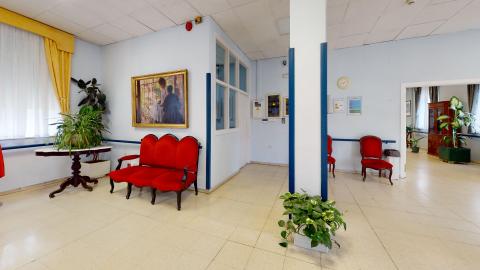 Estancia romántica. Perspectiva complementaria de la sala donde se aprecia otro cuadro de dos mujeres y otro sofá rojo de tres plazas. Un poco más a la derecha, en un muro más al fondo, hay otras dos sillas a juego.
