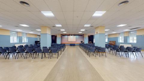 Salón de actos. Espacioso y luminoso salón pintado en azul y crema con sillas en azul.