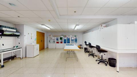 Amplia sala en blanco con mobiliario de almacenaje en blanco pegado a los muros. Al centro, una mesa de trabajo. Limpio y organizado.