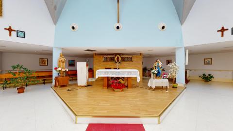 Capilla. Capilla con bancos de madera alineados a uno de los costados del altar. De frente, sobre una plataforma elevada en forma de trapecio con suelo laminado estilo madera, se sitúa el altar con un sagrario y motivos religiosos en la pared. En el muro que continua sobre el techo del altar, pintado en azul celeste, hay un gran crucifijo de madera. El resto de pintura y materiales están en blanco para resaltar el altar.