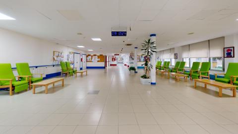 Sala de estar. Sala de estar amplia y muy luminosa pintada en blanco con algunos detalles en azul. Alrededor se acomodan sillones individuales ergonómicos de respaldo alto tapizados en piel sintética verde brillante con sus respectivas mesas bajas.