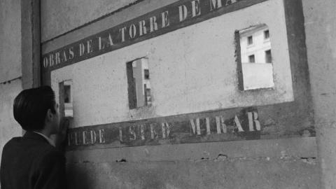 Imagen de un hombre de espaldas mirando a través de unos agujeros en una fachada
