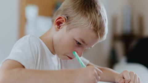 alumnos con discapacidad auditiva Un niño con audífonos en el aula