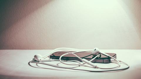 Móvil sobre una mesa que tiene enchufado unos cascos.
