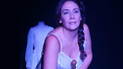 imagen de escena, muestra a la actriz en camisón y detrás de ella sobre un maniquí un vestido blanco de novia