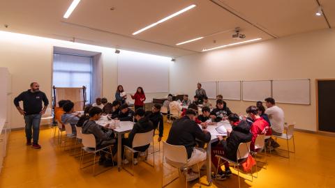 jóvenes en aula sentados por grupos con adulto de pie