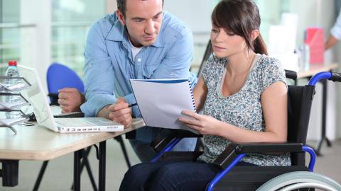 Jóven en silla de ruedas acompañada de asistente