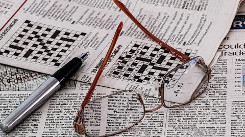 Periódico con bolígrafo y gafas encima