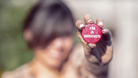 Mano sujetando una chapa con:  I'm a winner