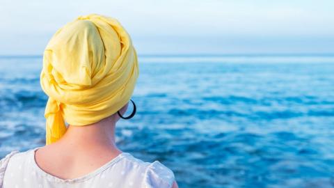 Imagen de mujer mirando al mar con pañuelo amarillo en la cabeza