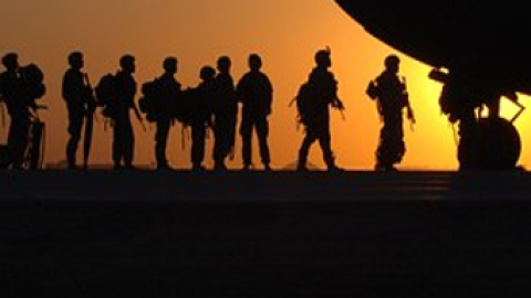 Siluetas de militares a contraluzen campaña junto a morro de avión