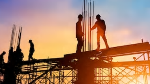 Trabajadores de la construcción a contra luz en estructura de acero de encofrados