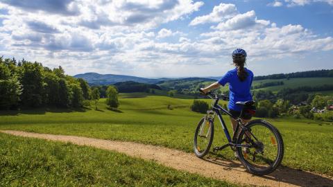 Ciclista de espaldas contemplando un paisaje verde