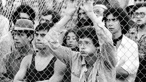 La adolescencia, 1996. © Jordi Socías, 2025 Varios jóvenes miran algo a través de una valla metélica