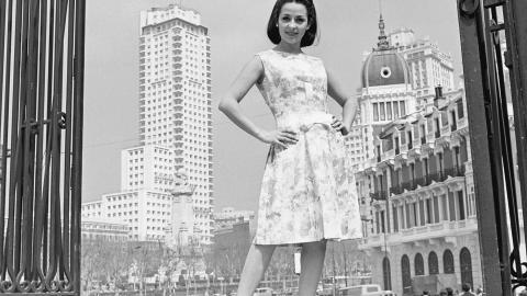 una mujer posa con un vestido de flores en una plaza