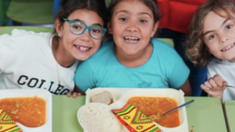 Cuatro niños comiendo en un comedor escolar