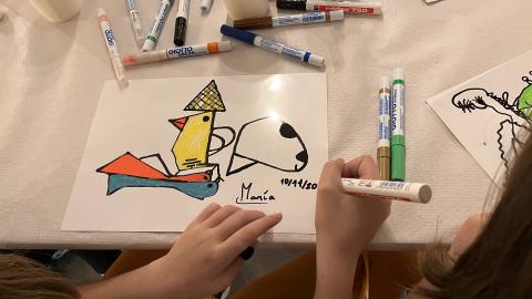 Manos de una niña firmando un dibujo
