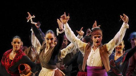 Grupo de bailarines en un escenario levantando las manos