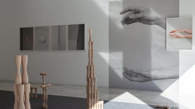 Fotografías de manos colgadas en una pared y juego infantil en madera sobre el suelo
