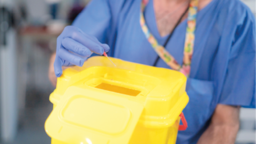 Sanitario depositando aguja en contenedor amarillo