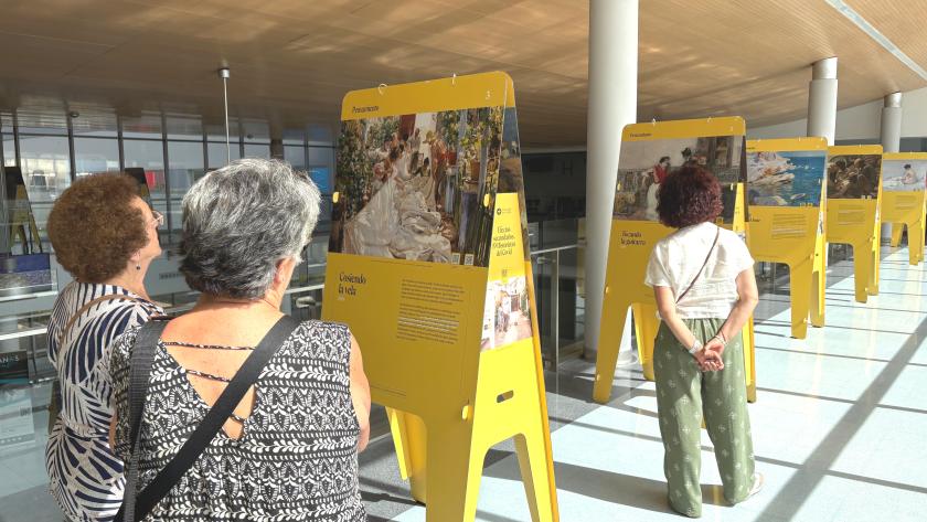 Tres mujeres contemplan una exposición pictórica en un hospital