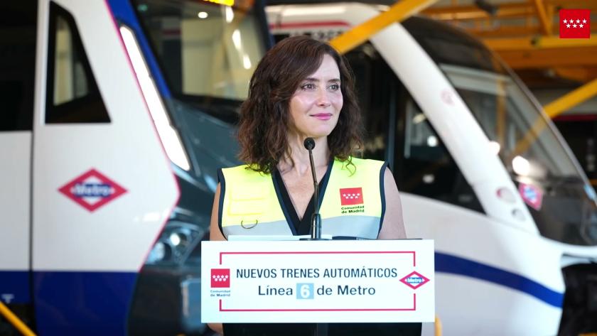 Isabel Diaz Ayuso con un tren detrás dando un discurso. 