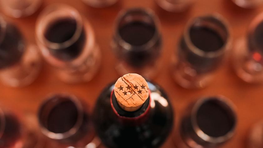 Botella de vino con un tapón de corcho con el símbolo de la Comunidad de Madrid rodeado de copas de vino
