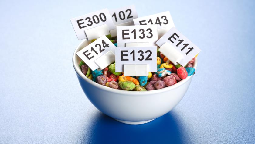 Taza de alimentos (caramelos de colores) con carteles que identifican los aditivos alimentarios que contienen