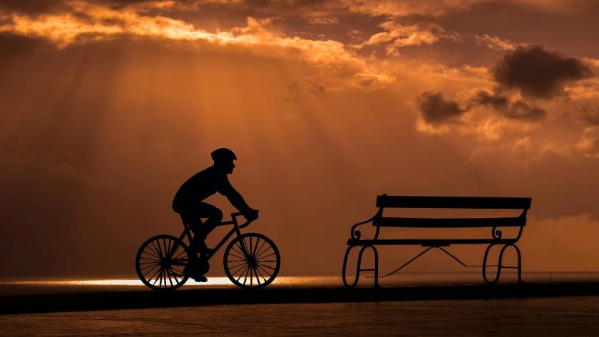 ciclista llegando a un banco al atardecer