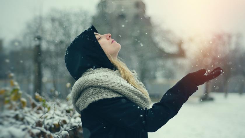 chica bajo la nieve observando los copos