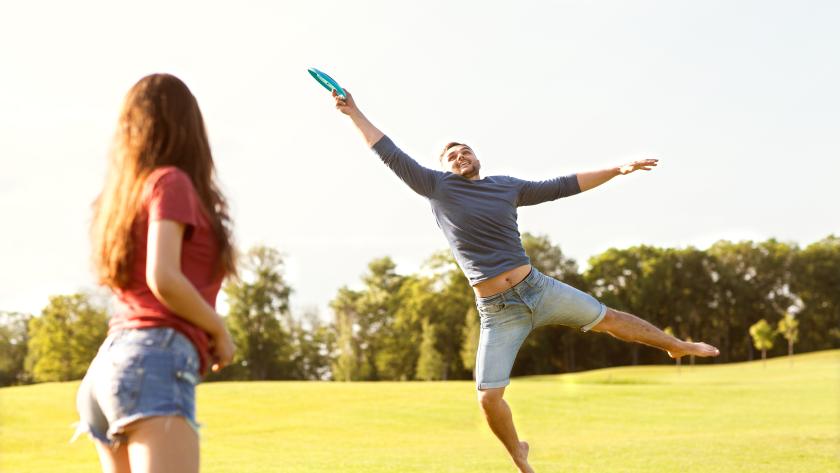 una chica y un chico jugando al plato volador en un parque