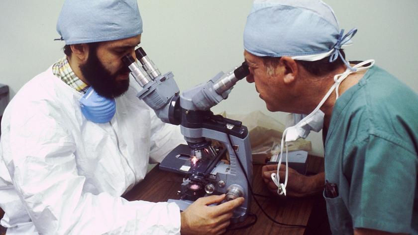 Dos médicos miran por dos visores del mismo microscopio